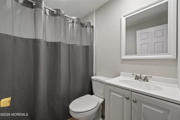 a view of an empty room with wooden floor and a ceiling fan