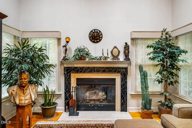 a living room with a fireplace and potted plants
