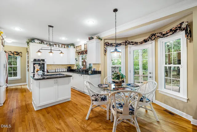 a kitchen with stainless steel appliances kitchen island granite countertop a table chairs and a wooden floor