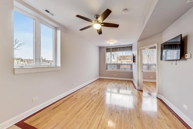 a view of an empty room with window and wooden floor