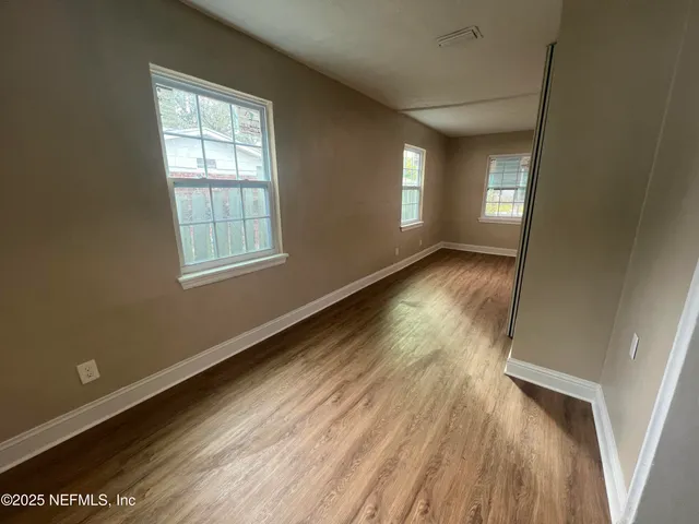 an empty room with wooden floor and windows