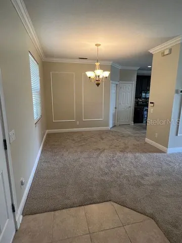 an empty room with chandelier fan and windows