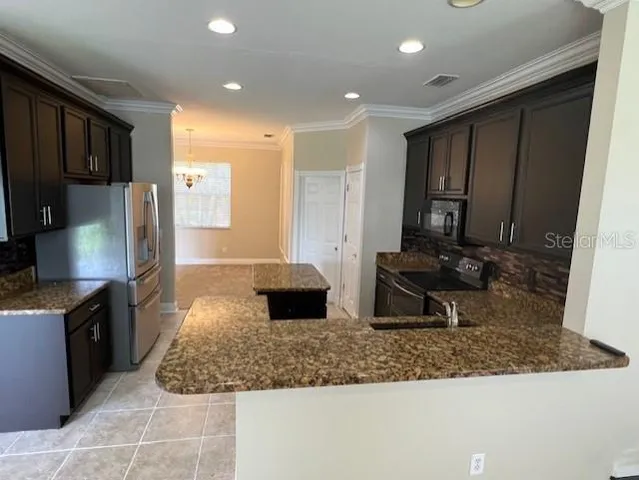 a kitchen with stainless steel appliances granite countertop a sink a stove and a refrigerator