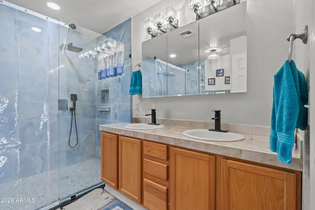 a bathroom with a granite countertop sink a mirror and shower