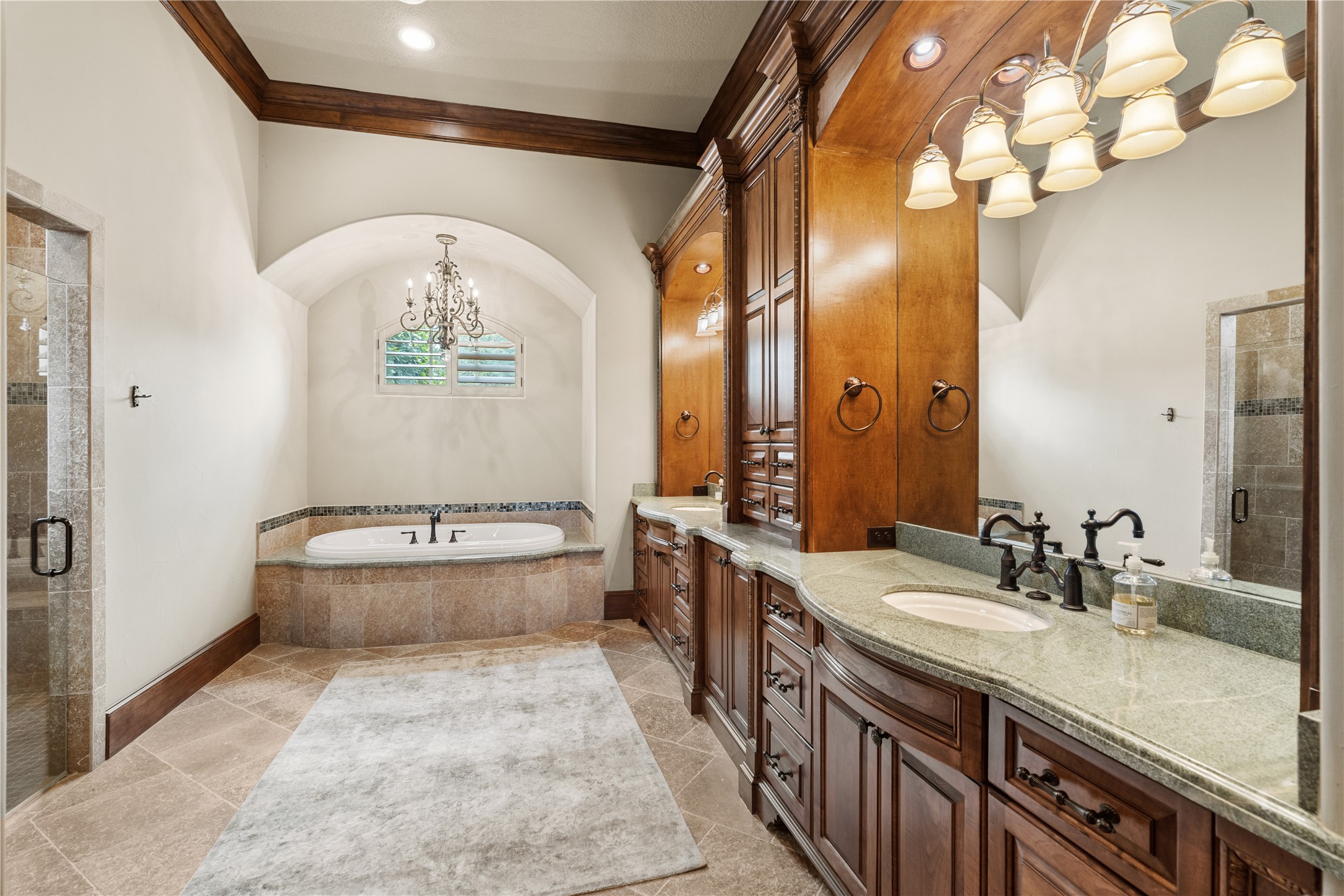 12349 Longmire Trace Conroe, TX 77304 - Photo 14 of 48 Spa-inspired primary bath with arched alcove soaking tub, rich cabinetry, and dual-sink vanity lighting.