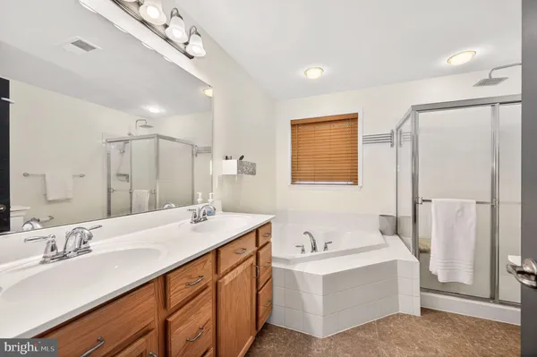 a bathroom with double vanity sinks a large mirror and a bathtub