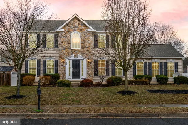 a front view of a house with garden and trees