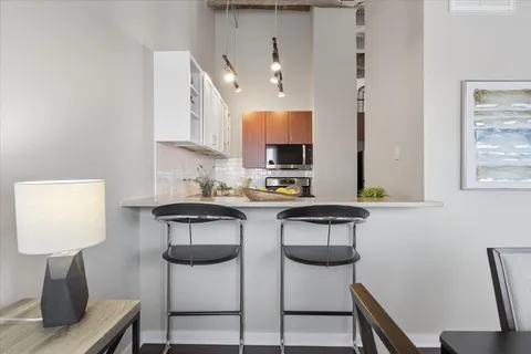 a kitchen with stainless steel appliances a sink a stove a table and chairs