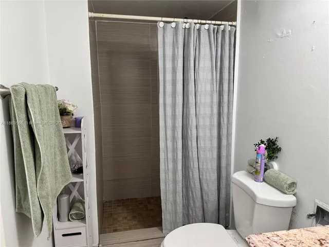 a white toilet sitting next to a shower curtain
