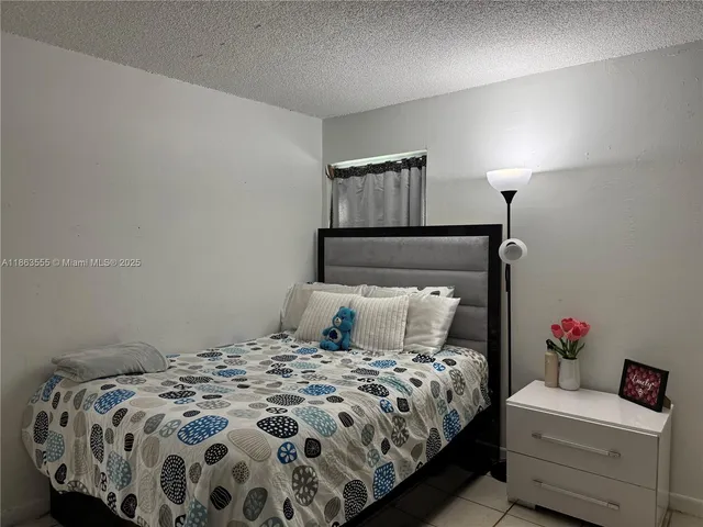 a bedroom with a bed and a lamp on the dresser