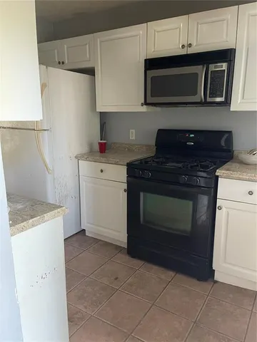 a kitchen with granite countertop white cabinets and stainless steel appliances