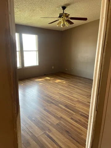 en empty room with windows and ceiling fan