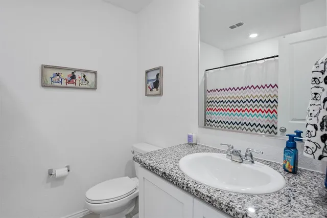 a bathroom with a granite countertop sink a mirror and a toilet