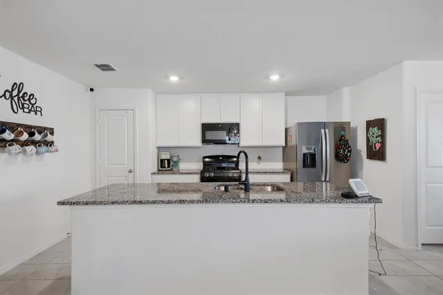 a kitchen with stainless steel appliances granite countertop a refrigerator a stove a sink a microwave and wooden cabinets