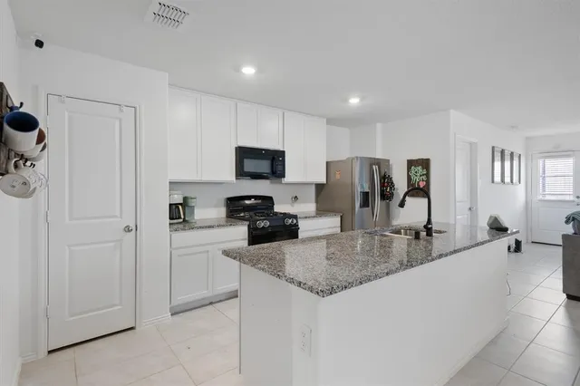a kitchen with kitchen island granite countertop a sink counter top space appliances and cabinets