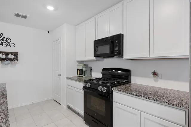a kitchen with granite countertop white cabinets stainless steel appliances and a counter space