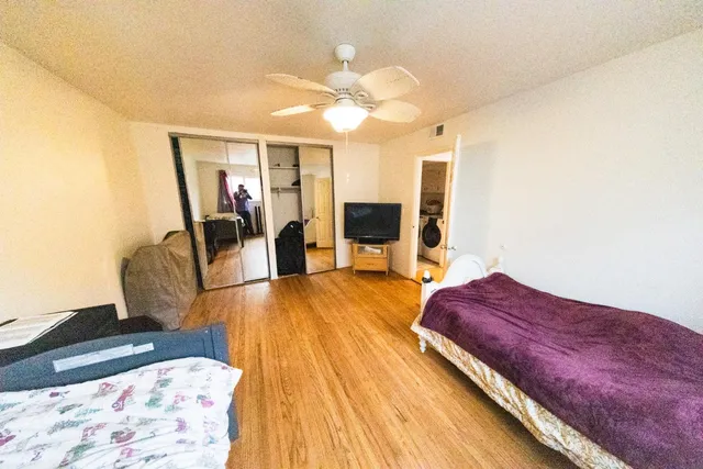 a spacious bedroom with a bed and wooden floor