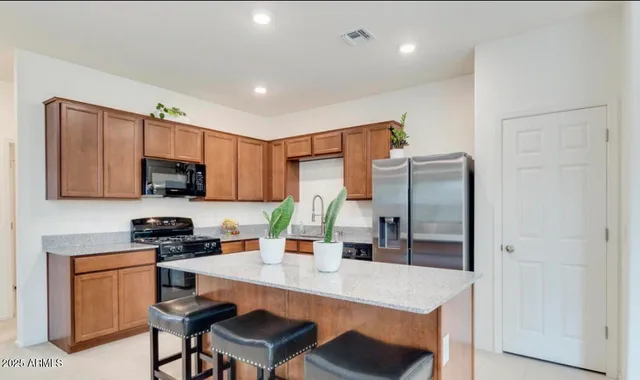 a kitchen with stainless steel appliances granite countertop a refrigerator a sink a stove a microwave a dining table and chairs with wooden floor