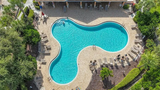 an aerial view of a swimming pool with outdoor seating and yard