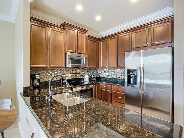 a kitchen with kitchen island granite countertop a sink refrigerator and microwave