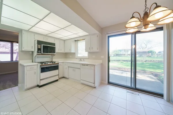 a kitchen with a stove a sink dishwasher a microwave oven and a dining table with wooden floor