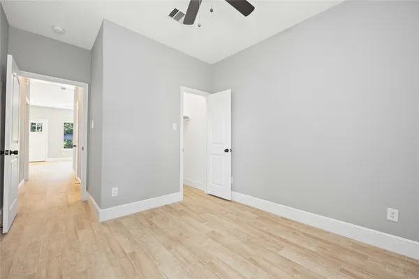 a view of a hallway with wooden floor and a chandelier fan
