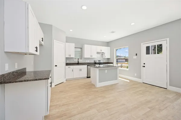 a kitchen with granite countertop white cabinets and white appliances