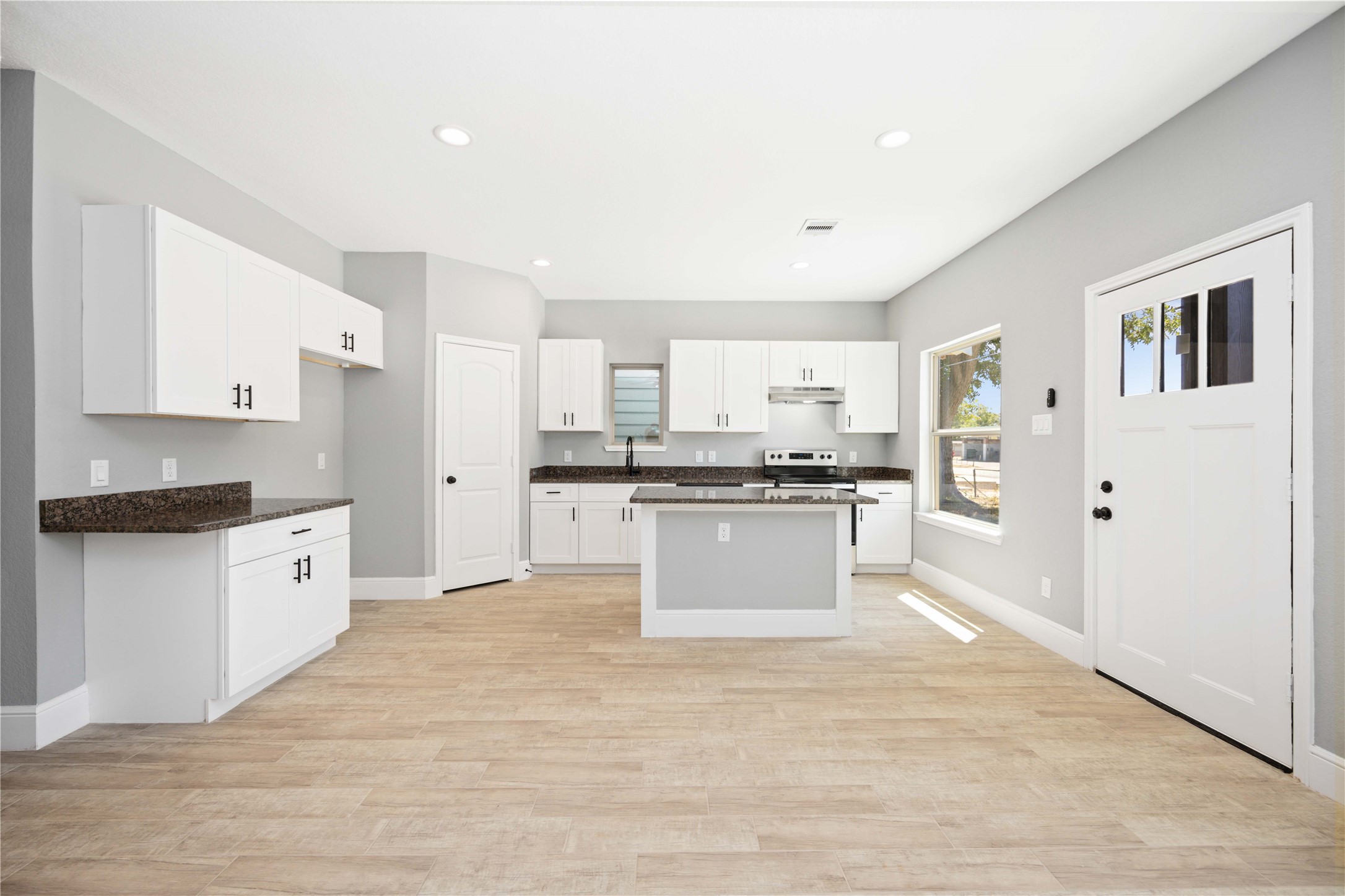 4651 Mallow Street, Unit B Houston, TX 77051 - Photo 5 of 22 a large kitchen with kitchen island a sink dishwasher a refrigerator and white cabinets with wooden floor