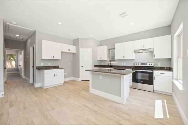 a kitchen with granite countertop a stove top oven and cabinets