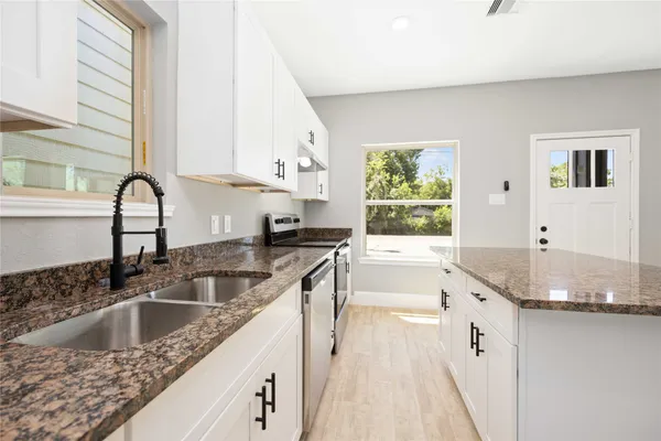 a kitchen with granite countertop a sink a counter top space and cabinets