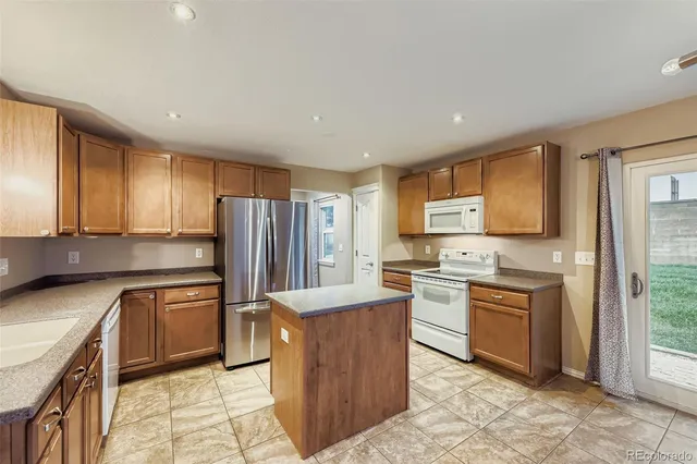 a kitchen with stainless steel appliances granite countertop a stove top oven a sink dishwasher a refrigerator and cabinets with wooden floor