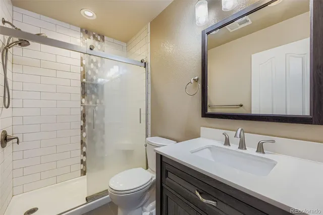 a bathroom with a granite countertop sink toilet and shower