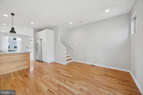 a view of kitchen and empty room with wooden floor