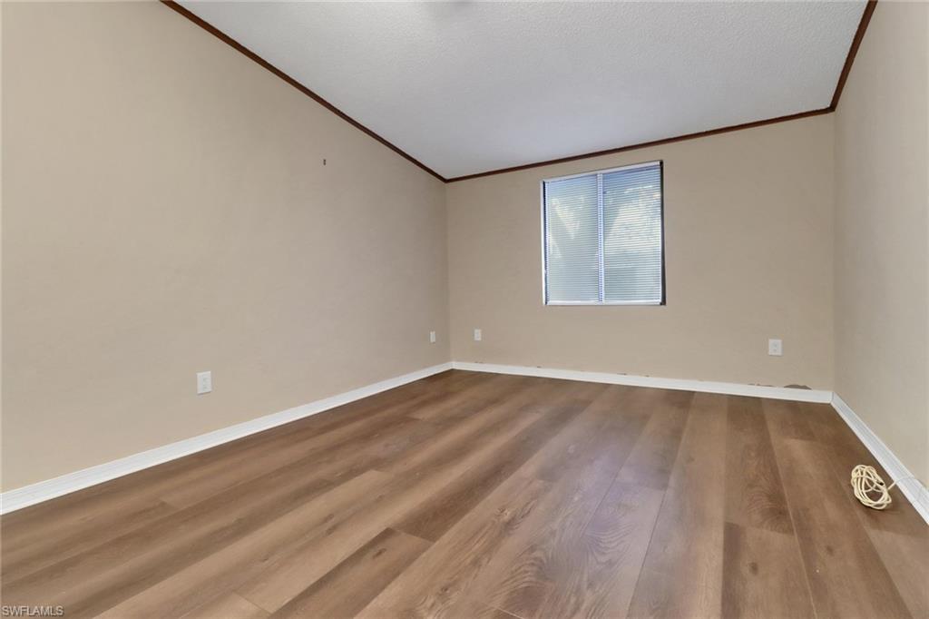 5214 Treetops Drive, Unit I Naples, FL 34113 - Photo 18 of 18 an empty room with wooden floor and windows
