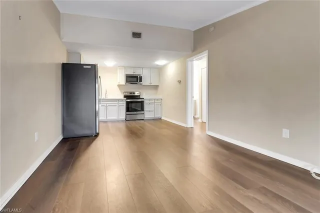 a view of kitchen with stainless steel appliances wooden floor and chair