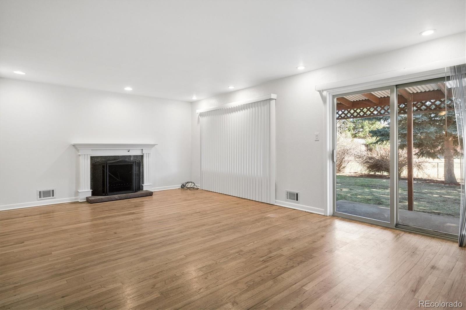 6640 South Williams Circle West Centennial, CO 80121 - Photo 2 of 23 an empty room with wooden floor and fireplace