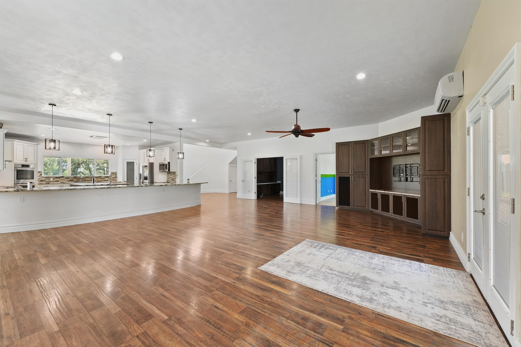 43919 Austin Branch Road Hempstead, TX 77445 - Photo 12 of 48 From this vantage point in the spacious living room, you’ll enjoy a sweeping view that captures the heart of the home. To one side, elegant French doors lead into a private study featuring custom-built cabinetry and a thoughtfully designed desk—ideal for working from home or managing daily tasks in style. Just beyond, the chef’s kitchen steals the show with its striking custom island, equipped with modern pop-up outlets and surrounded by high-end finishes.
