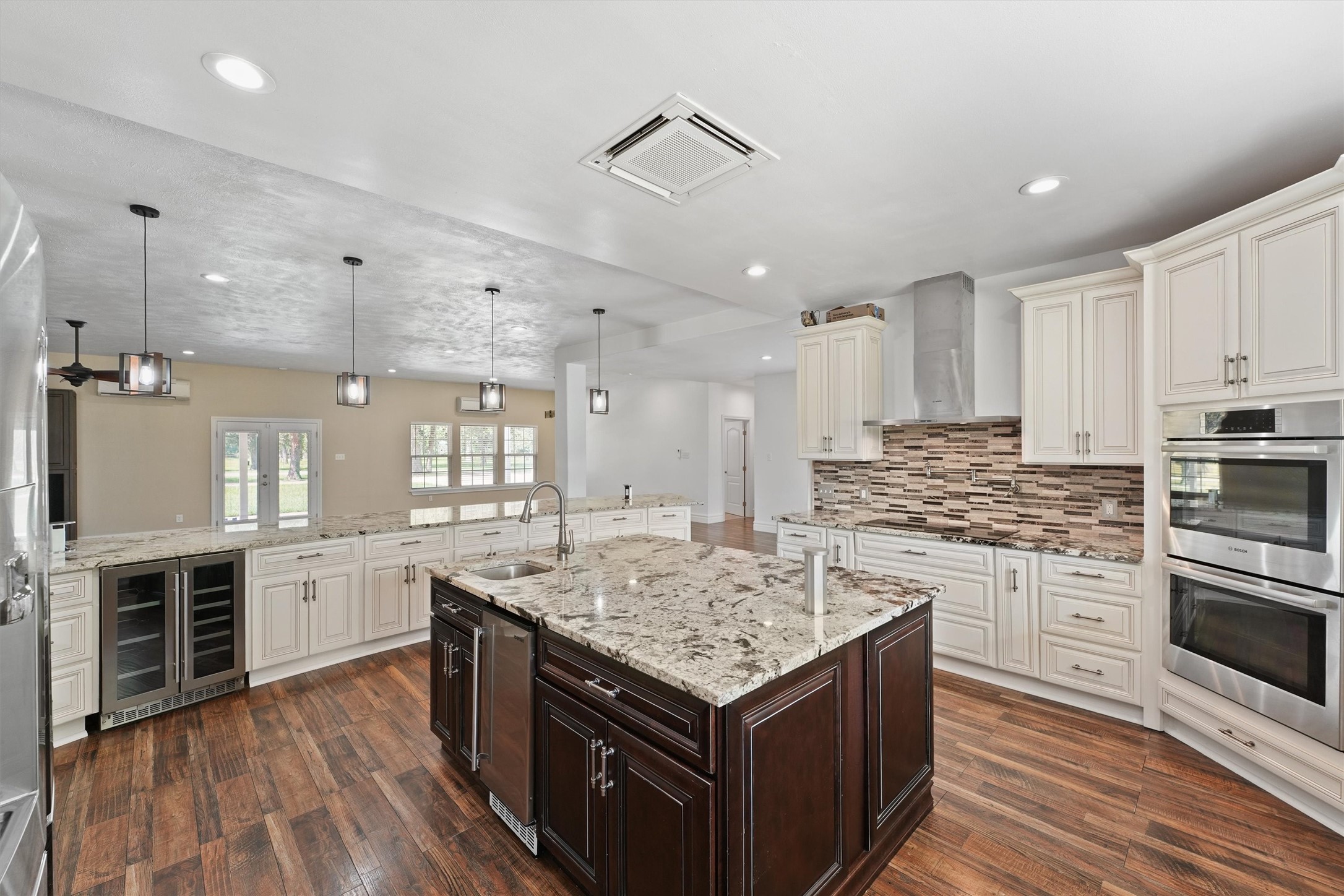 43919 Austin Branch Road Hempstead, TX 77445 - Photo 17 of 48 The oversized island not only serves as a central gathering space but also houses a built-in wine and beverage cooler—perfect for entertaining. High-end appliances include a double oven and a sleek pot-filler faucet over the cooktop for ultimate convenience. Every cabinet is custom-built with soft-close technology, offering smart storage solutions wrapped in timeless design. From everyday meals to gourmet creations, this kitchen delivers an elevated experience at every turn.