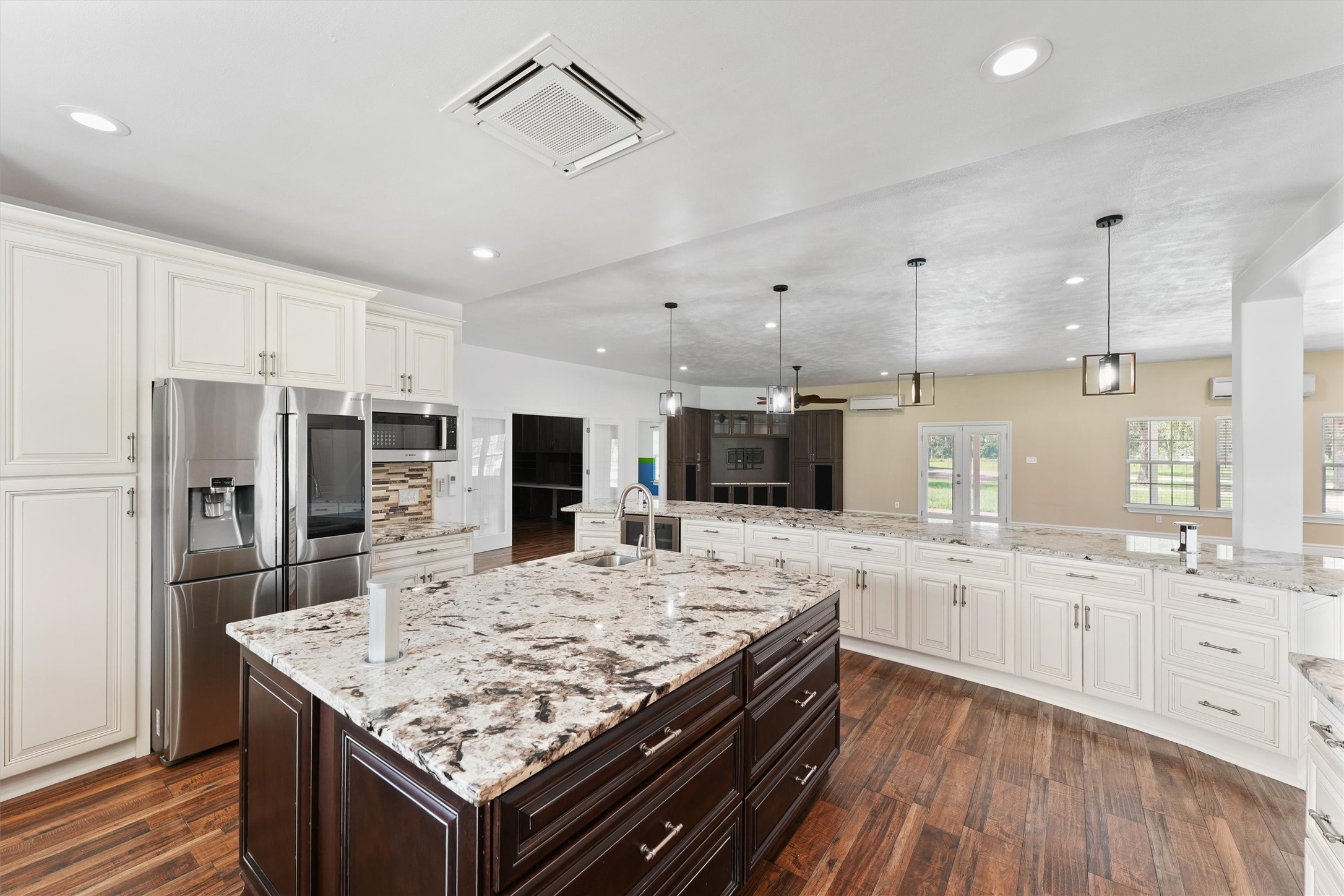 43919 Austin Branch Road Hempstead, TX 77445 - Photo 18 of 48 The oversized island not only serves as a central gathering space but also houses a built-in wine and beverage cooler—perfect for entertaining. High-end appliances include a double oven and a sleek pot-filler faucet over the cooktop for ultimate convenience. Every cabinet is custom-built with soft-close technology, offering smart storage solutions wrapped in timeless design. From everyday meals to gourmet creations, this kitchen delivers an elevated experience at every turn.