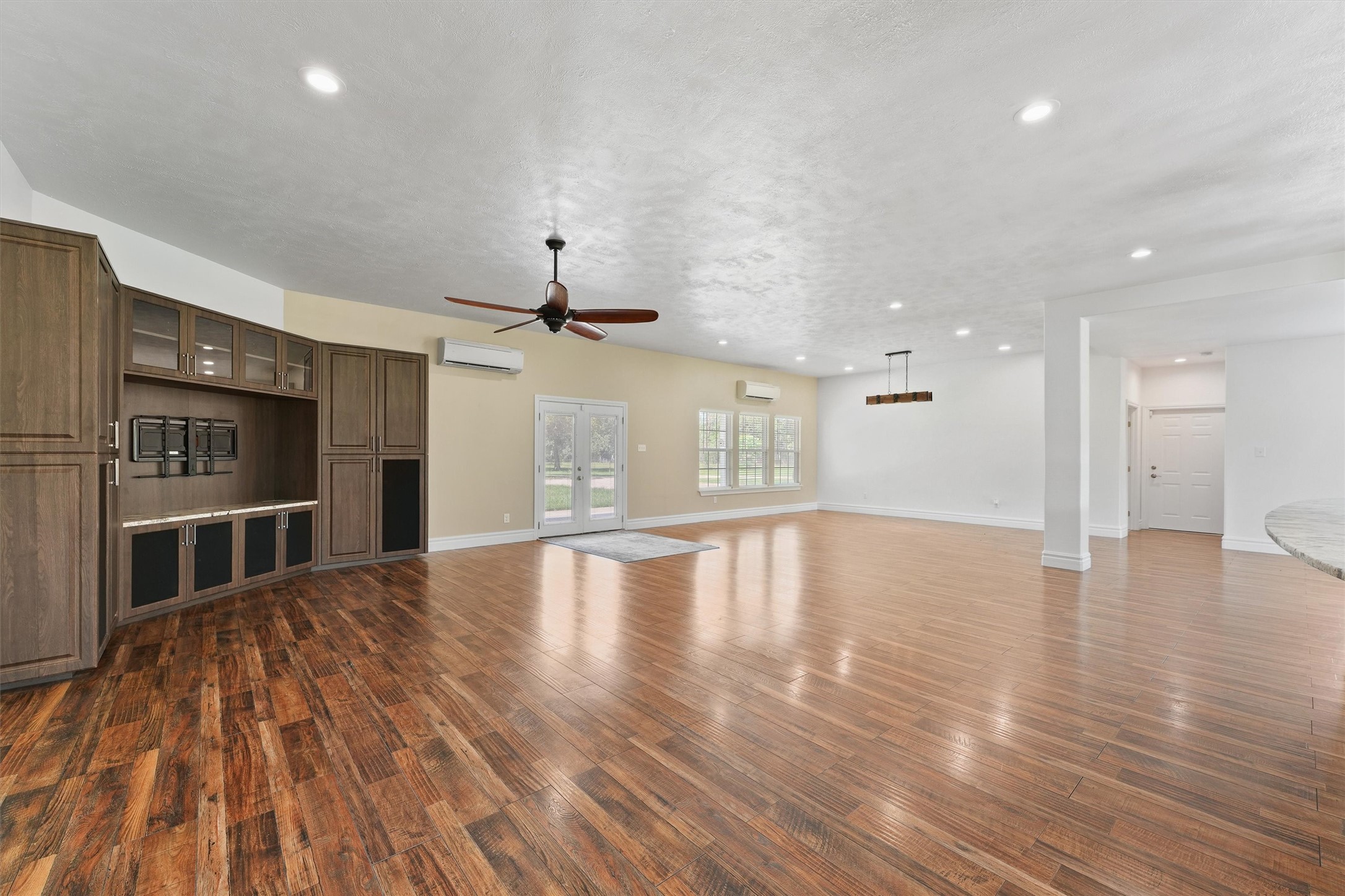 43919 Austin Branch Road Hempstead, TX 77445 - Photo 10 of 48 The heart of the home welcomes you with a generous living space designed for both everyday comfort and unforgettable entertaining. Anchored by a stunning custom-built entertainment center, this room offers the perfect blend of function and refined farmhouse charm. The open layout flows seamlessly into the formal dining area and cozy breakfast nook, all bathed in natural light from thoughtfully placed windows that frame the surrounding landscape.