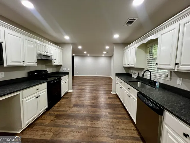 a large kitchen with granite countertop lots of counter space and stainless steel appliances