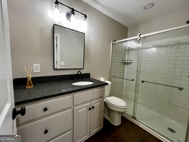 a bathroom with a granite countertop sink toilet and shower