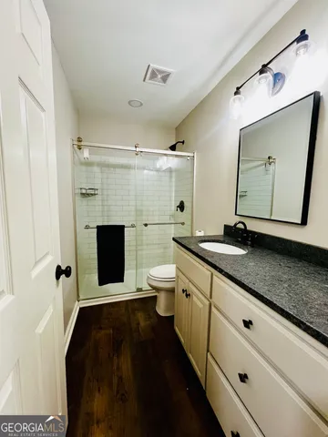 a en suite bathroom with a granite countertop toilet sink and a mirror