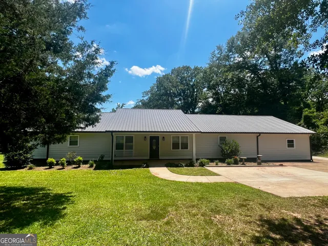 a front view of a house with a garden and trees