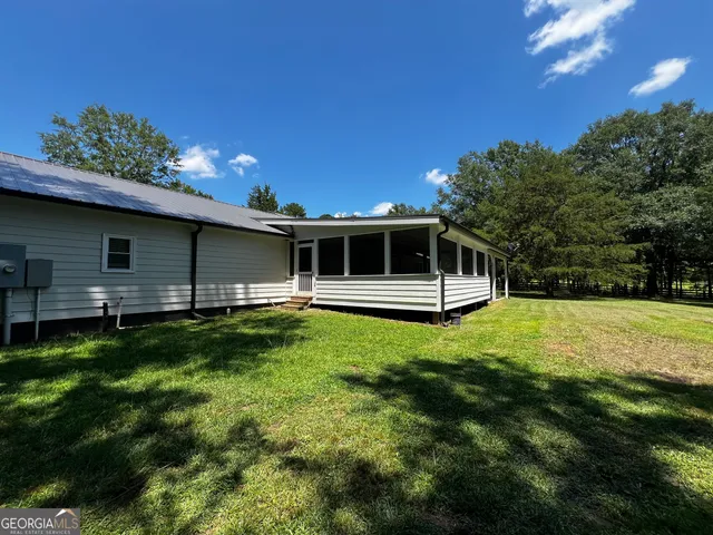 a backyard of a house with large trees and plants