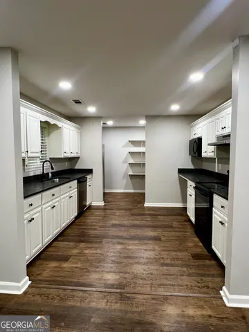 a kitchen with granite countertop a refrigerator and stove top oven