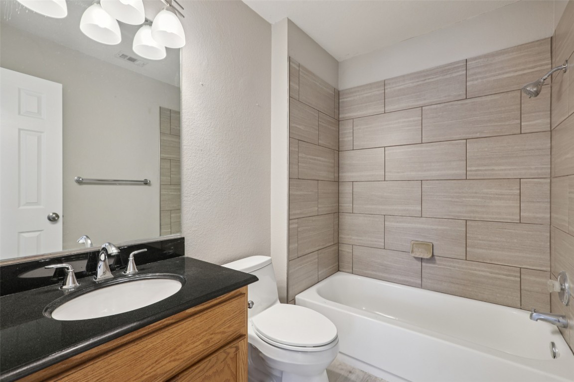 4937 Hartson Kyle, TX 78640 - Photo 32 of 40 a bathroom with a granite countertop sink toilet mirror and bathtub