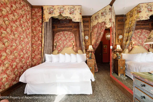 a large white bed in a small room next to a window