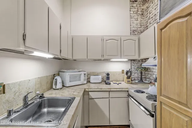 a kitchen with stainless steel appliances granite countertop a sink a stove and a white cabinet