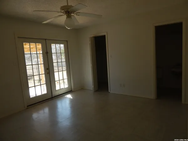 an empty room with windows and ceiling fan